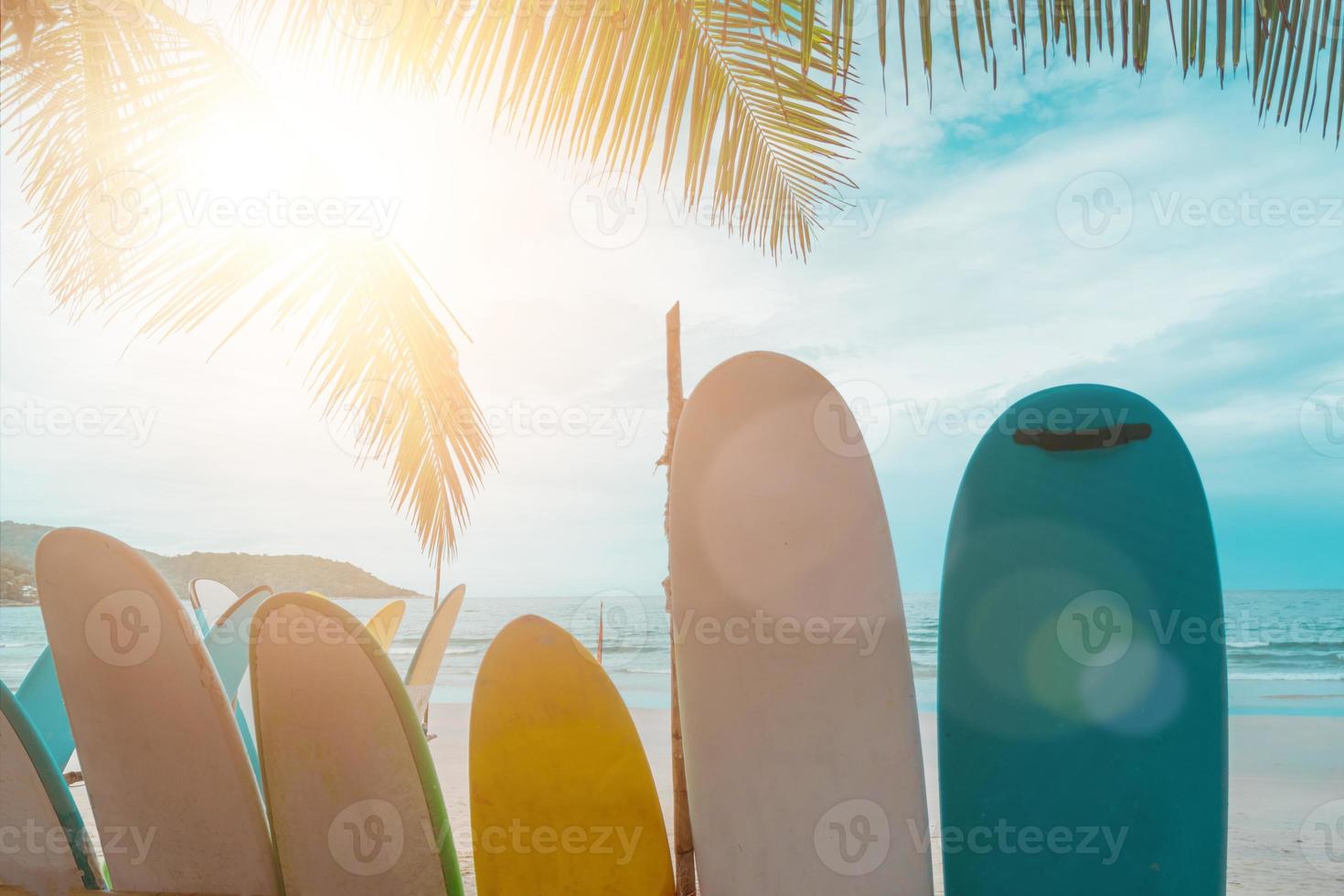 muchas tablas de surf en alquiler en la playa de verano con cielo azul de la luz del sol. foto