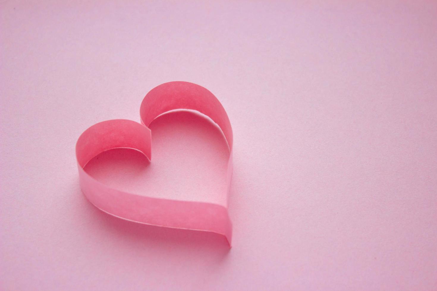 Beautiful pink paper heart on pink background with copy space. Quilling, origami, handmade. Minimalism photo