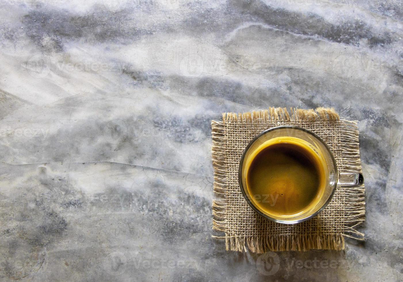 vista superior taza de americano negro sobre tela de saco y mesa de hormigón rústico. el buen sabor bebe de un café arábica orgánico. concepto de actualización matutina foto