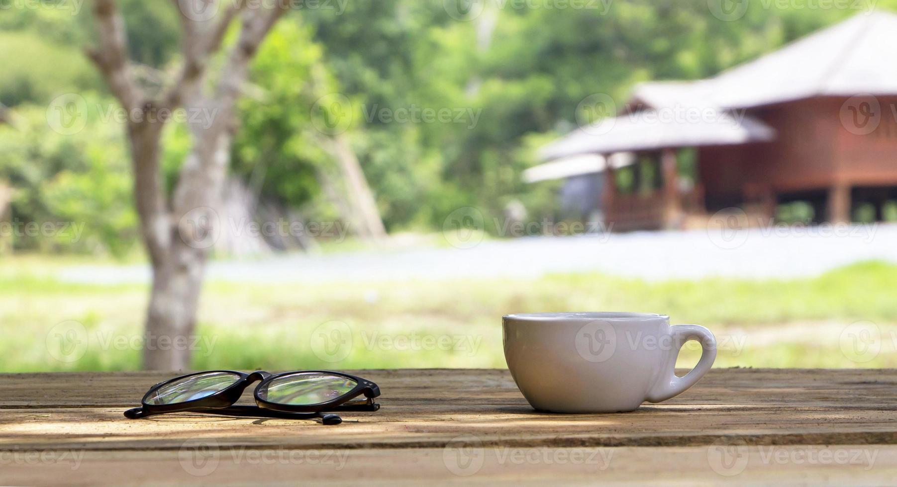 Cup of coffee on wooden plank in natural background photo