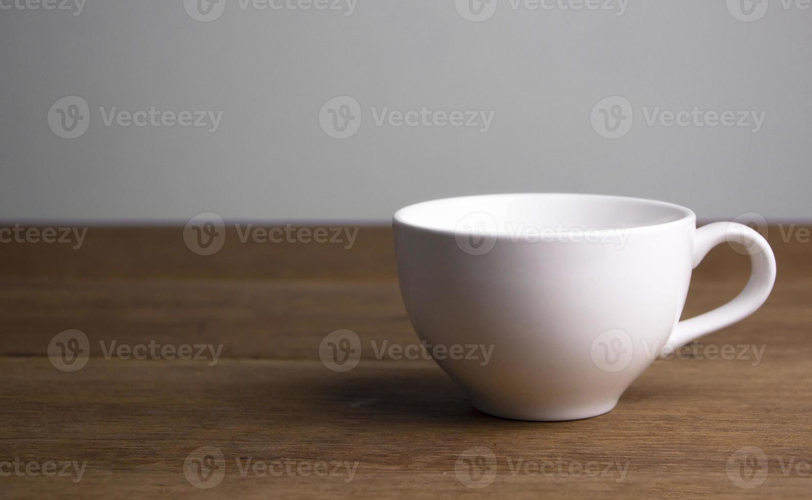 Front view of  white ceramic coffee cup on a brown rustic wooden table. photo