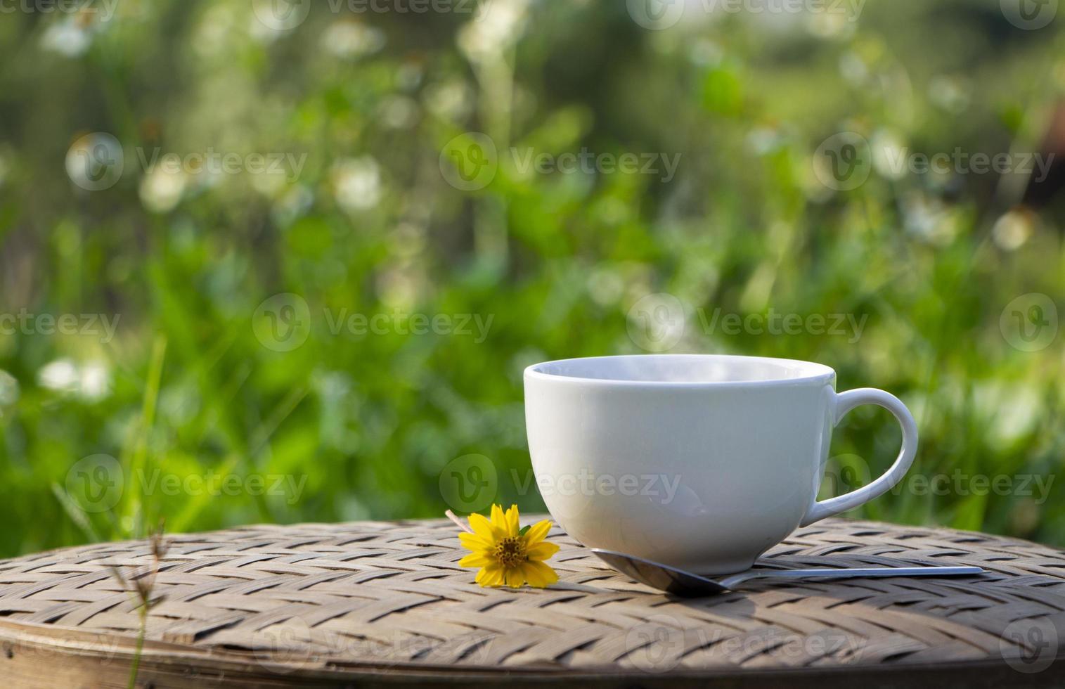 taza de cerámica blanca de café negro con buen humo encima de una taza y luz solar matutina, fondo natural. buenos días con un concepto de bebidas refrescantes foto