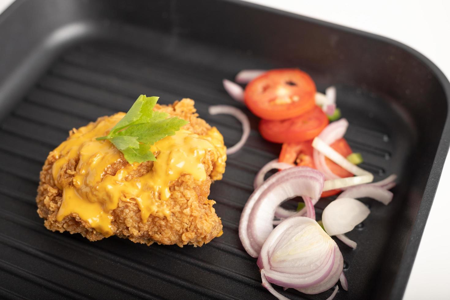 Chicken fried topped cheese in a black pan photo