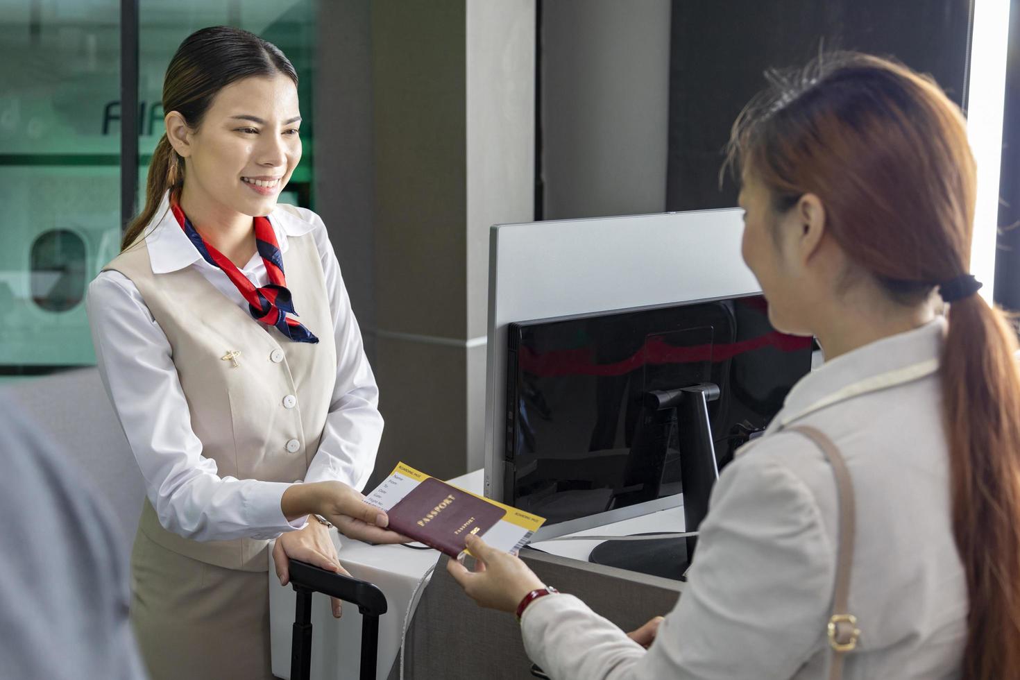 Asian passenger is showing her boarding pass to the airline ground crew at departure gate into the airplane for final inspection before boarding the plane photo