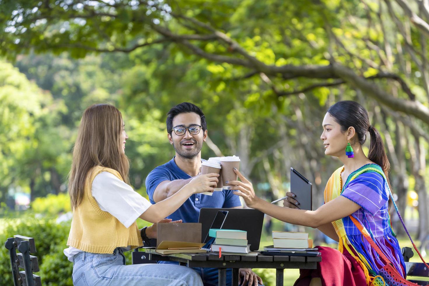 un grupo de estudiantes universitarios se reúne y trabaja en una tesis y un proyecto afuera en el jardín del campus universitario durante el verano foto