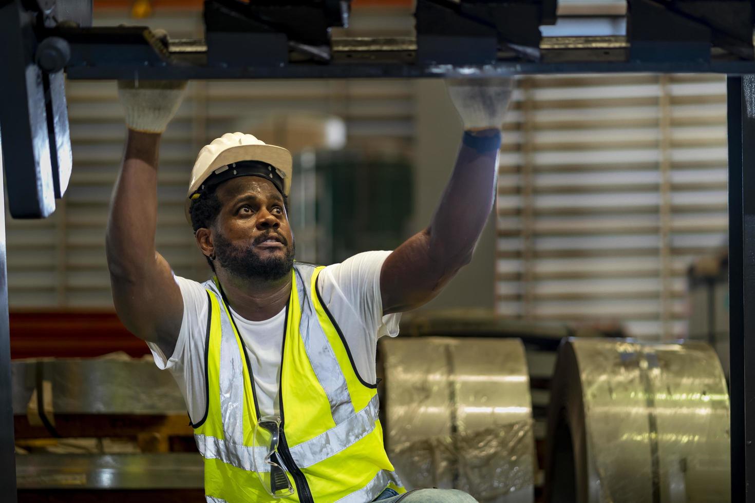 African American mechanic worker is checking the gear for hydraulic machine inside metal steel manufacturing factory for maintenance and inspection concept photo