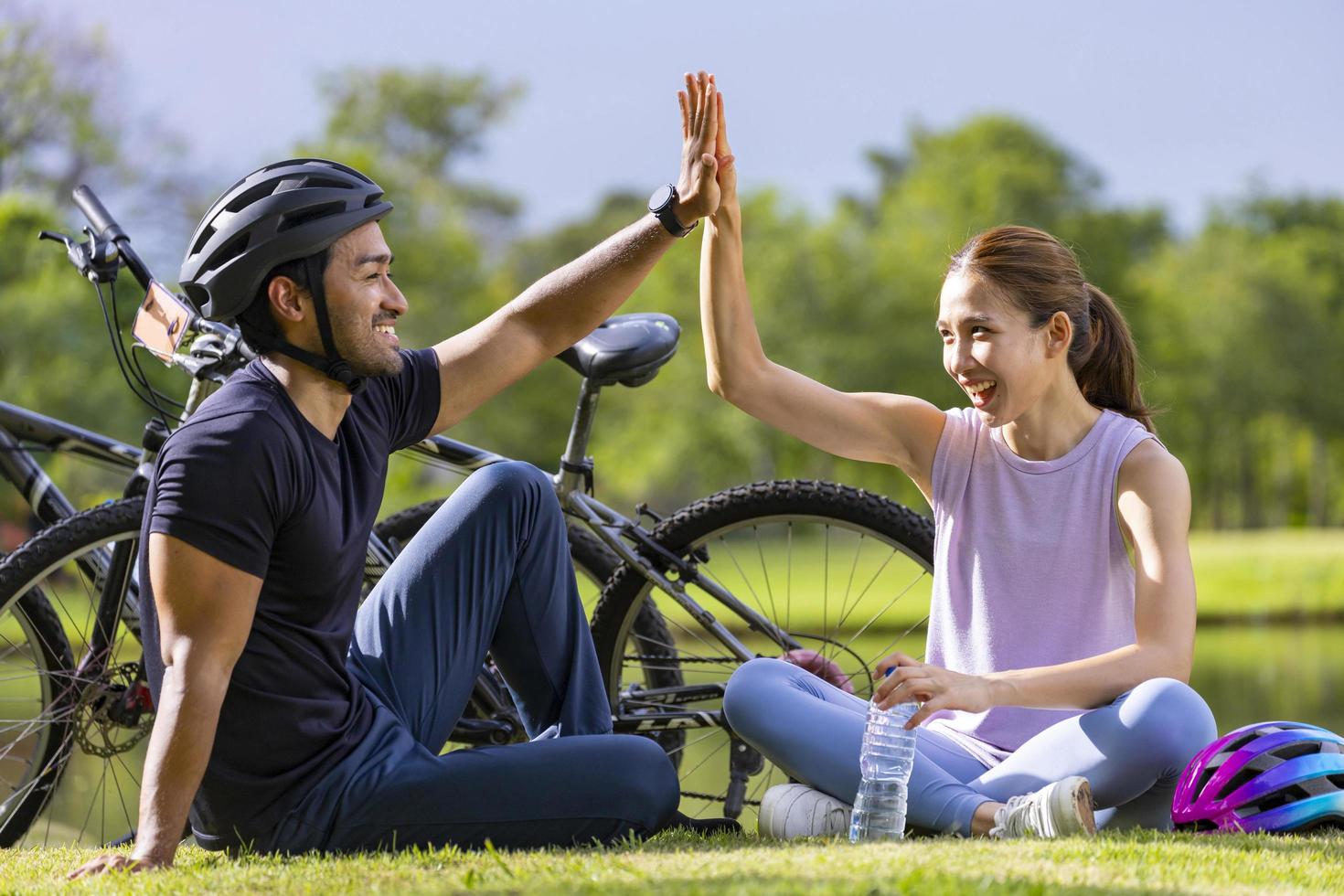 joven pareja asiática dando cinco después de andar en bicicleta en el parque público para actividades de ejercicio de fin de semana y concepto de búsqueda recreativa foto