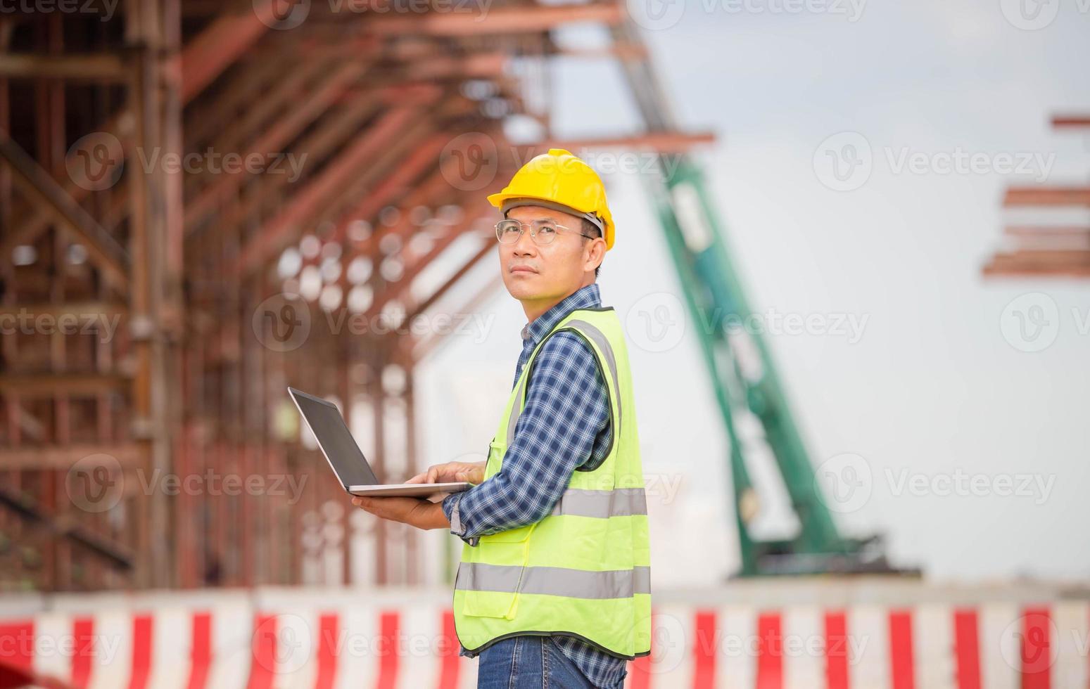 Engineer checking project at the building site, Man in hardhat with laptop at the infrastructure construction site photo