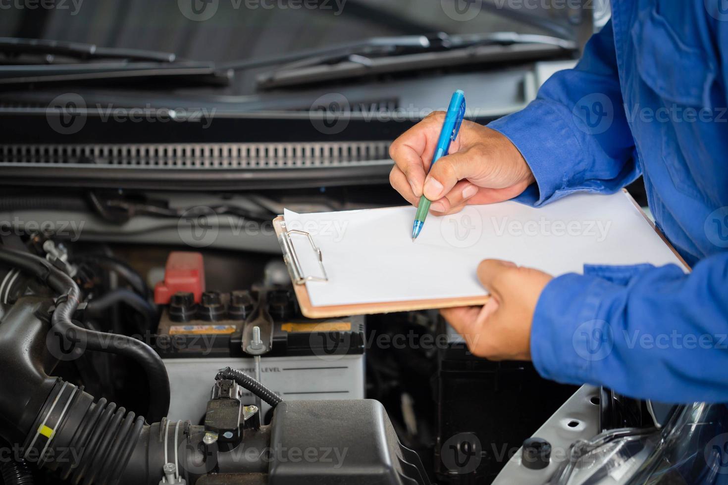 Auto mechanic holding clipboard checklist the car at mechanic shop, Mockup blank clipboard, Technician doing the checklist for repair machine a car in the garage photo