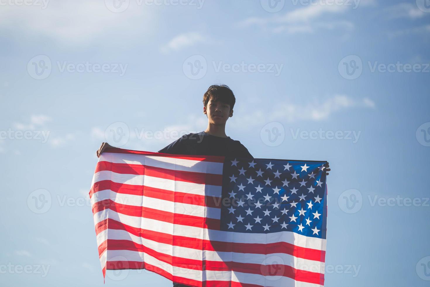Silhouette of boy holding USA flag, man is holding waving american USA flag photo