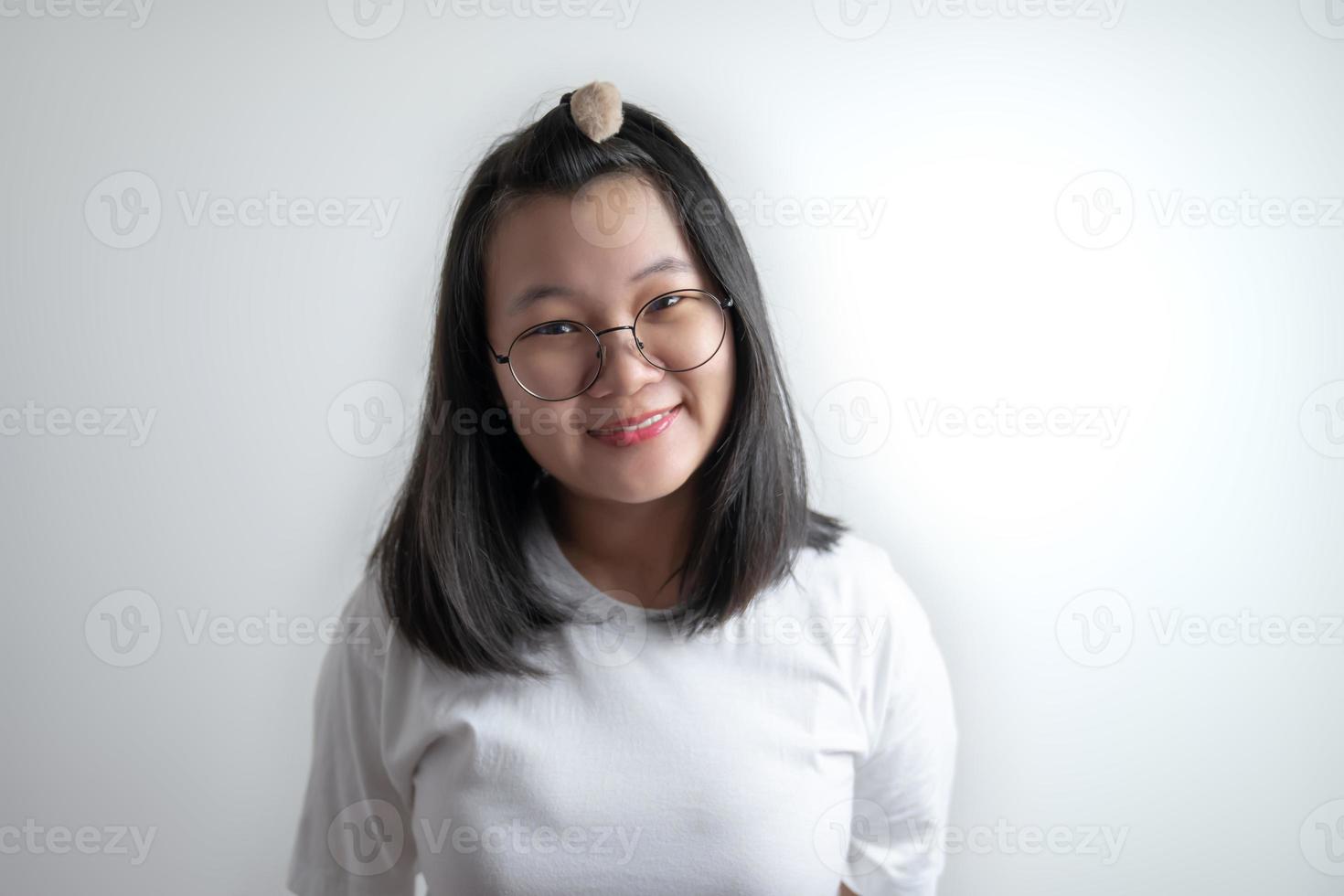 retrato de una joven asiática bonita con sus anteojos y una camiseta blanca casual en un estudio de fondo blanco claro y claro. foto