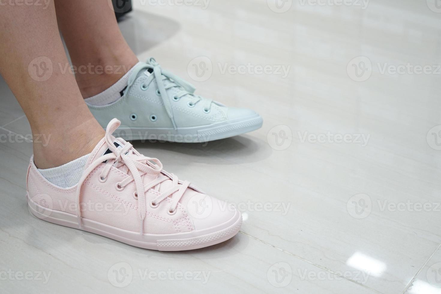 gal intenta zapatillas de deporte en tonos pastel y color en una zapatería deportiva y de moda. foto