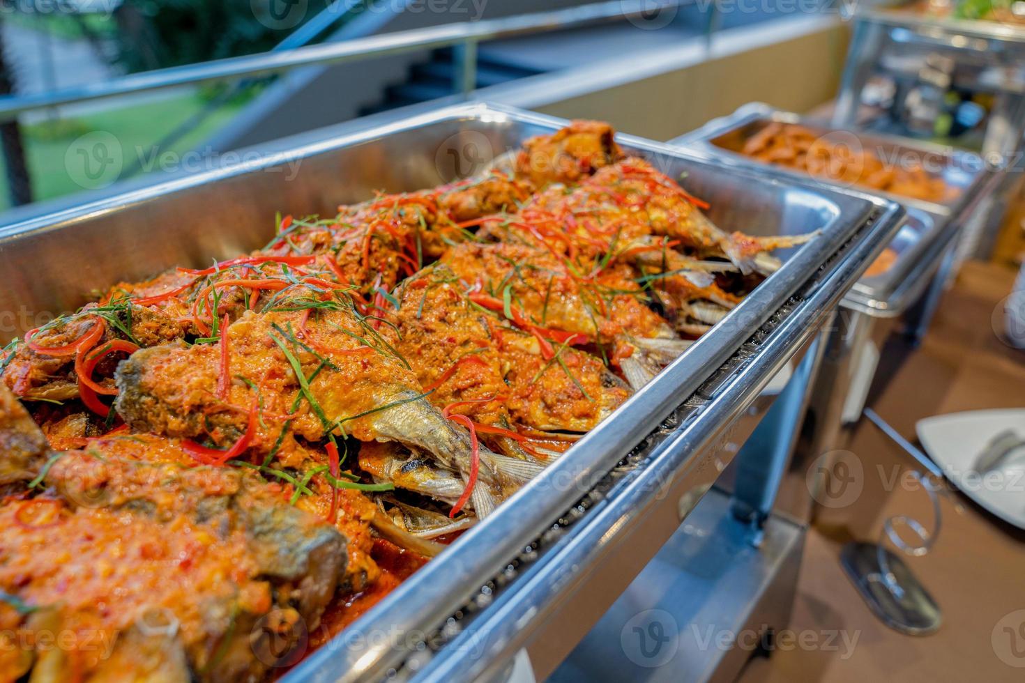 un pescado de comida tailandesa salteado en una salsa picante en un plato triangular de aluminio en el buffet de línea frente a la sala de seminarios. foto