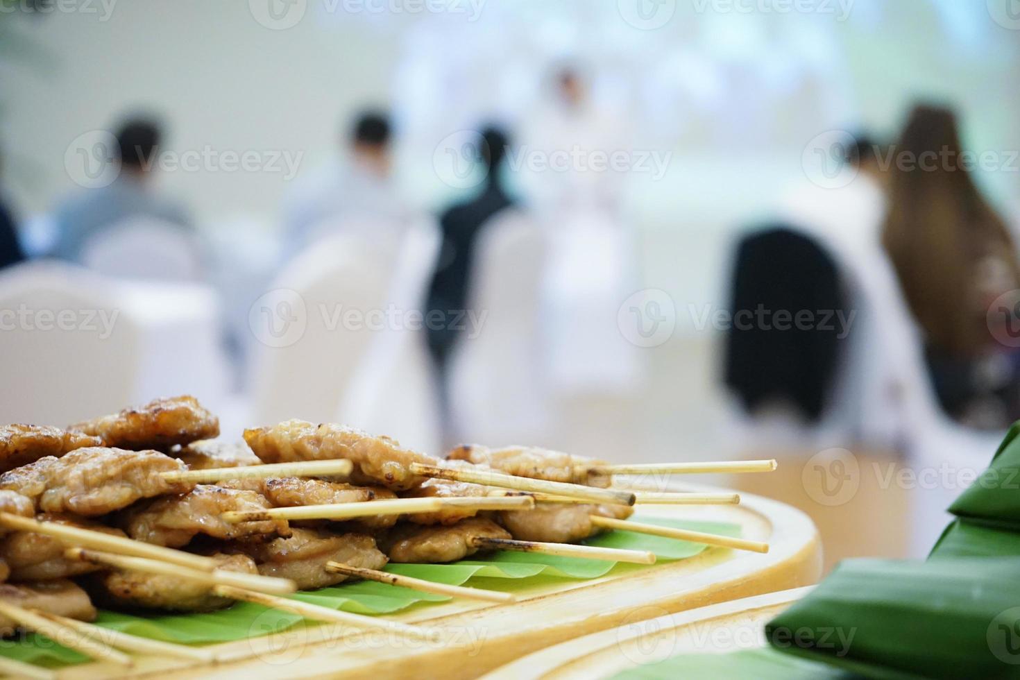 cooked grilled roasted pork sticks are arranged on the banana leaf behind the seminar  training hall and prepared for a seminar breaking time inside meeting hall. photo