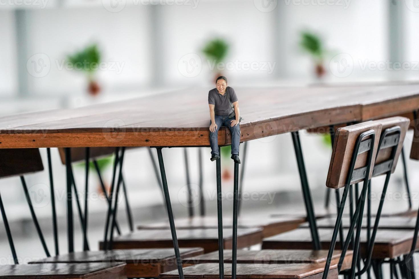 Tiny relax camera guy sitting at the corner of the dark vintage table with blur background. photo