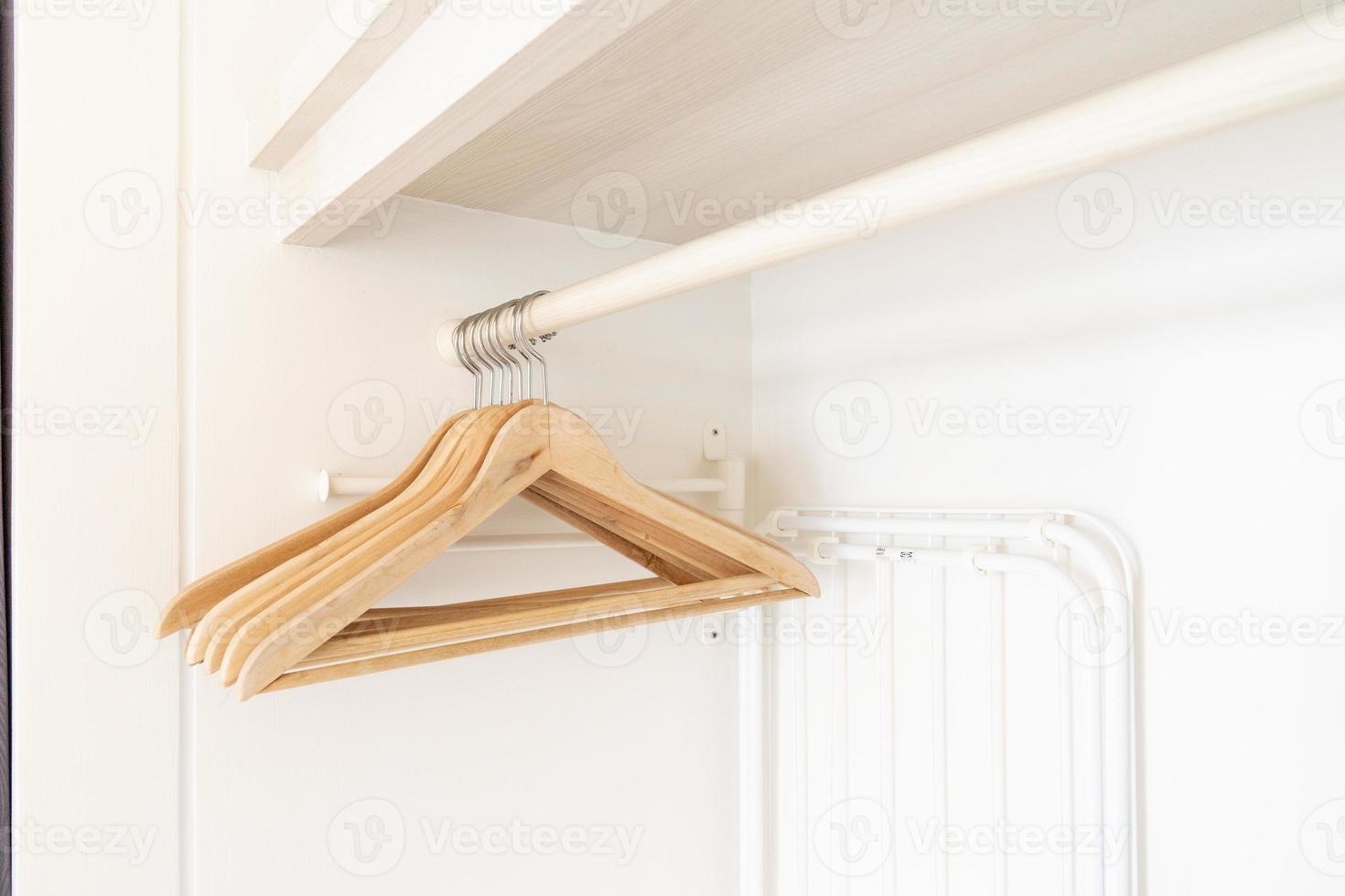 Wooden Cloth hangers are hung with empty cloth in the white wardrobe. photo