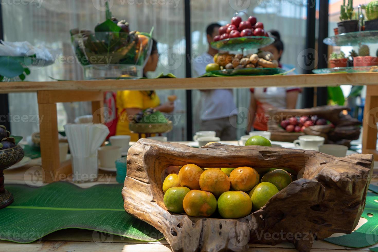 Variedad de frutas como rambután, naranja, mangostán, ciruela roja en la barra de mostrador de madera para la gente del seminario al aire libre en el jardín de Tailandia. foto