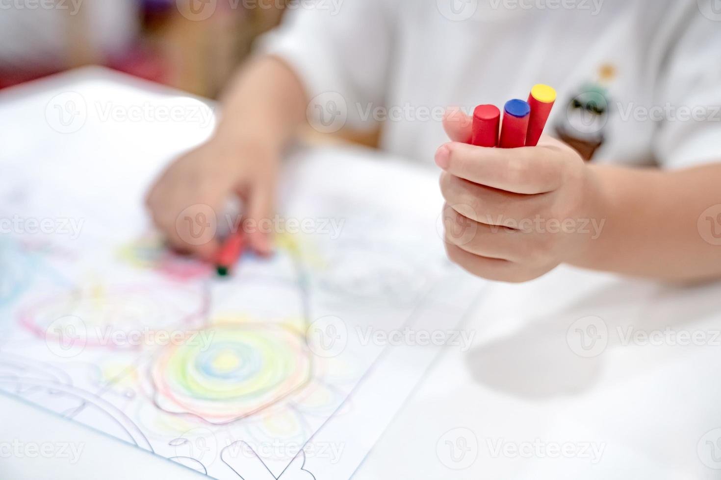 little girl plays and learns to coloring Crayon on the paper in the ice-cream restaurant., Bangkok, Thailand. photo