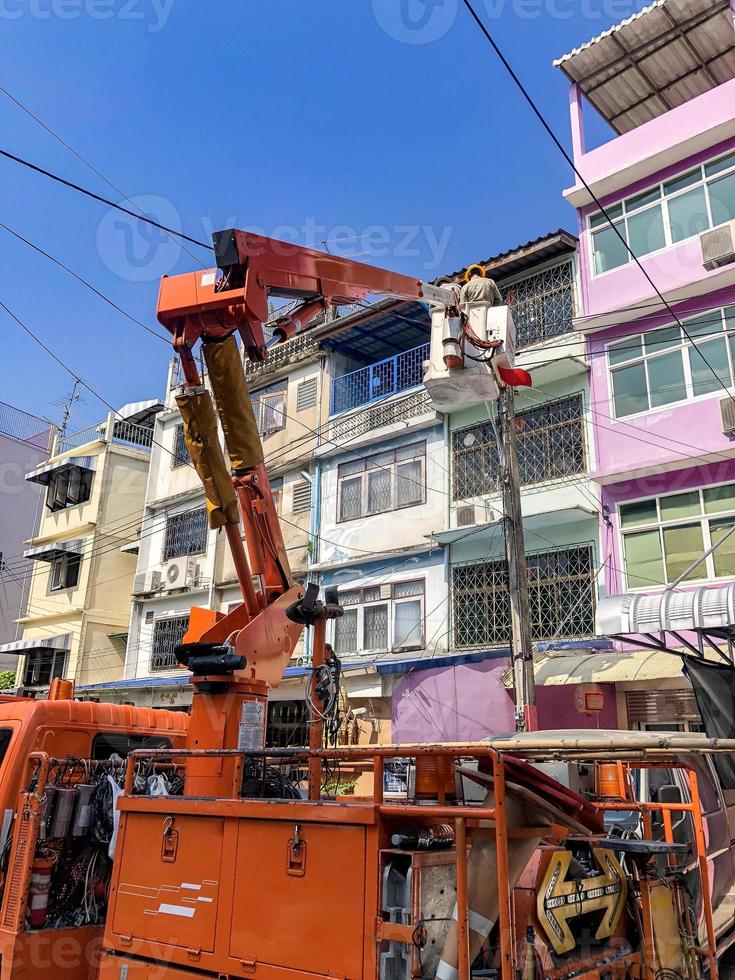 Electrician on the truck crane shifted up to check and repair main electric power line in Soi ManSri area, PomPrab, Bangkok, Thailand. photo