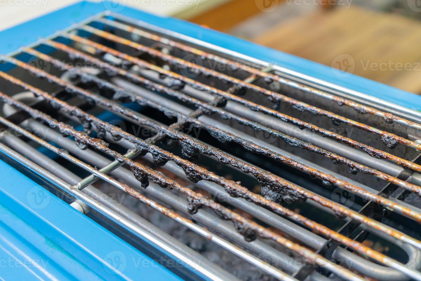 Dirty black mark burned on grilled above blue electric stove from oil or fat pork roasted grilled. photo