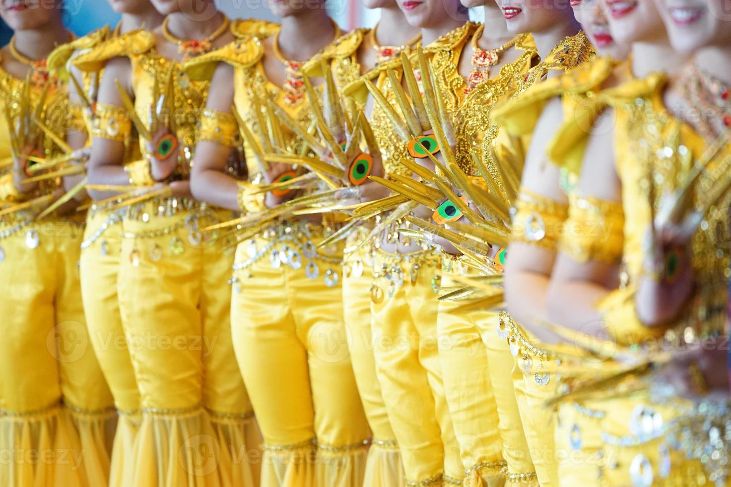 Performance traditional show, with the amazing luxury yellow Indian dress style., They are posting and standing in a row of photo shooting section.