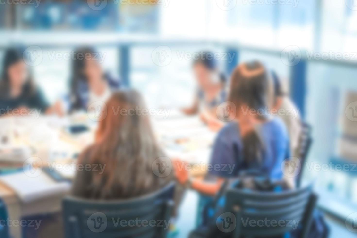 las adolescentes borrosas solo se sientan alrededor de la mesa en los grandes almacenes, cantina con muchos libros y apoyo tecnológico. foto