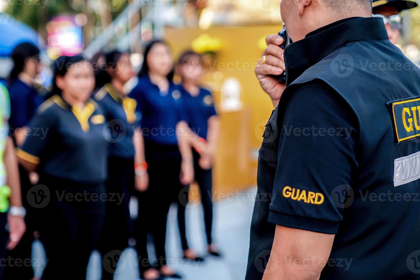 head of security guard call meeting and talk into walkie talkie for communication to the team. photo