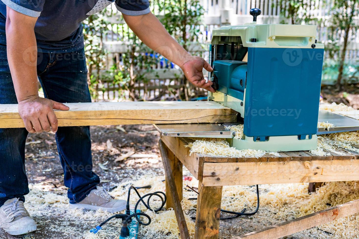 worker scrubs the big long wood plate with polishing machine in the garden. photo