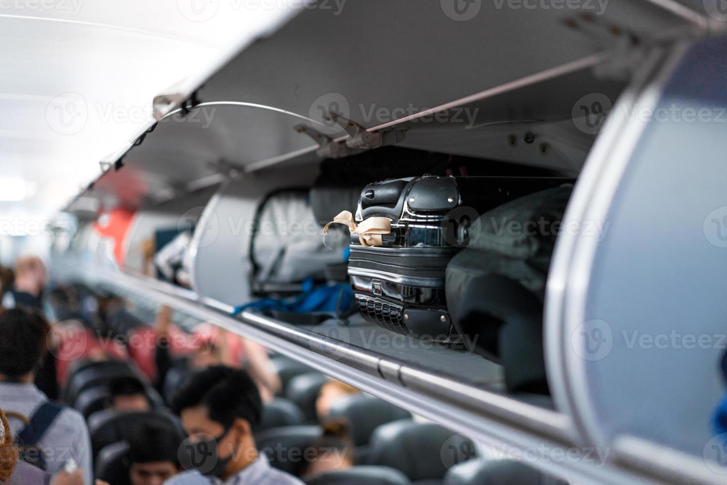 luggage on airplane shelf overhead passenger seat photo