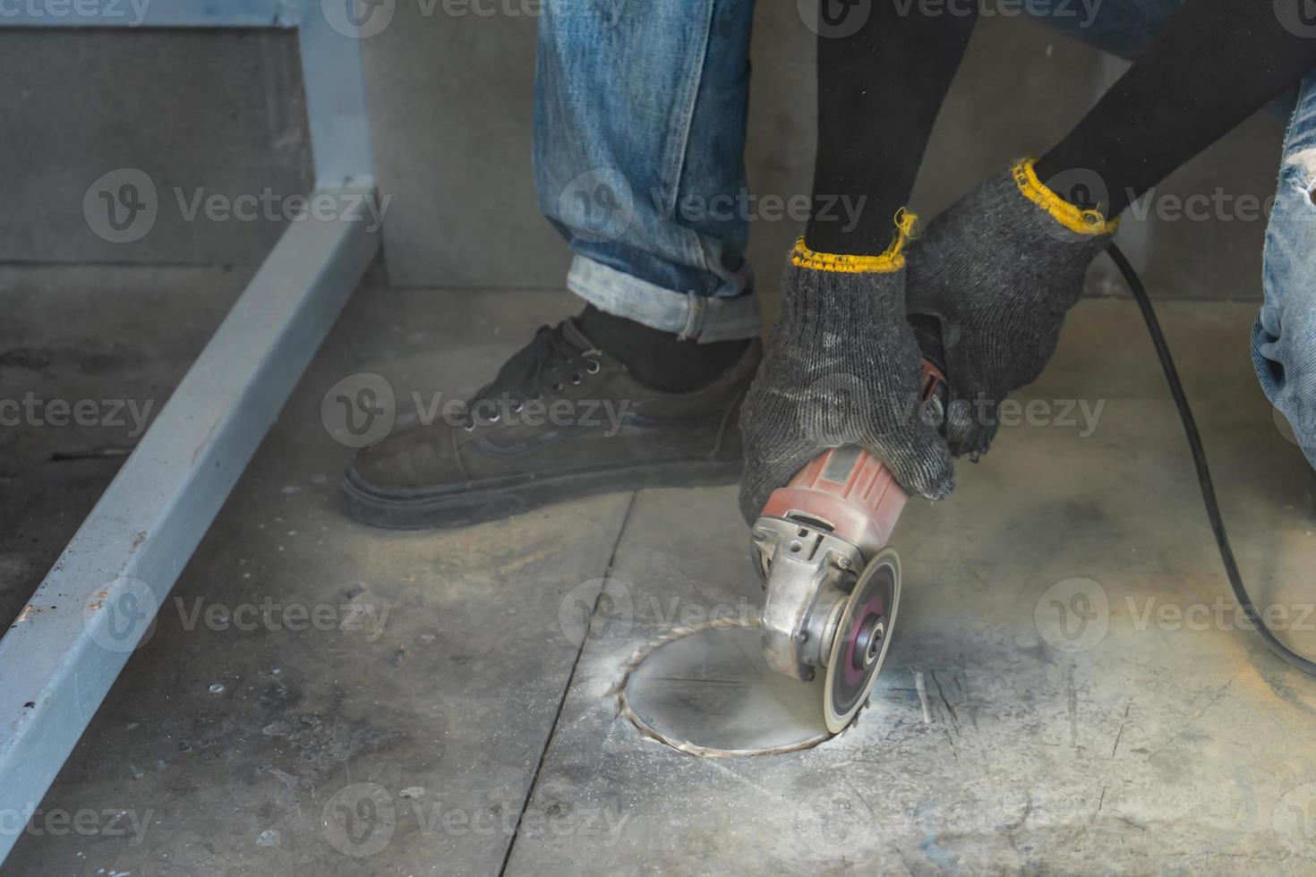 el trabajador de la construcción está cortando el piso con una máquina de hoja mediana para mantener la forma circular con mucho polvo alrededor para instalar el armario. foto