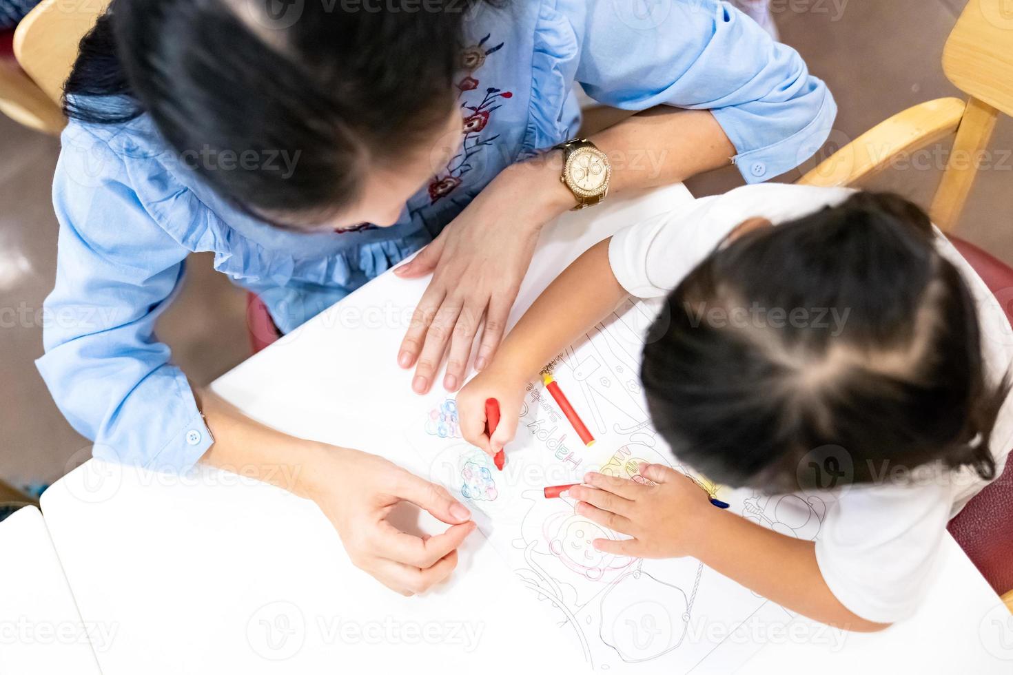 little girl plays and learns to coloring Crayon on the paper in the ice-cream restaurant., Bangkok, Thailand. photo