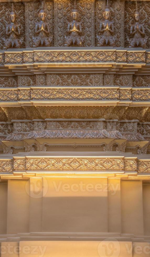 Gold small Thai God on the golden square pole with the warm light in Thailand Temple. photo