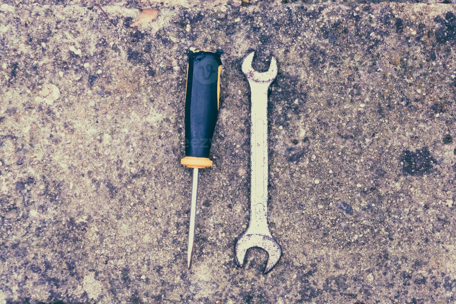 Wrench and hole punch tool on concrete photo