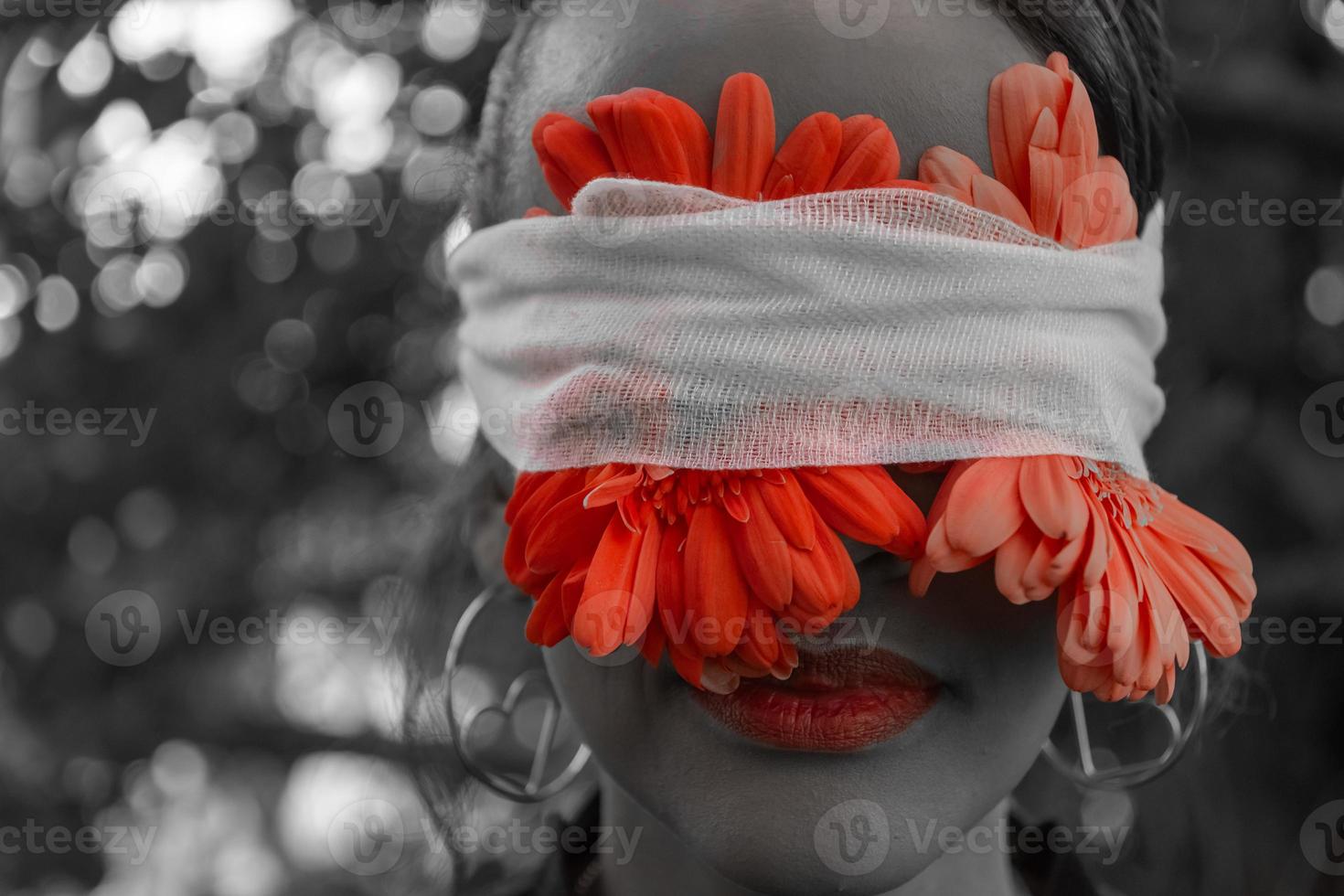 Woman with red flowers bandaged to her eyes photo