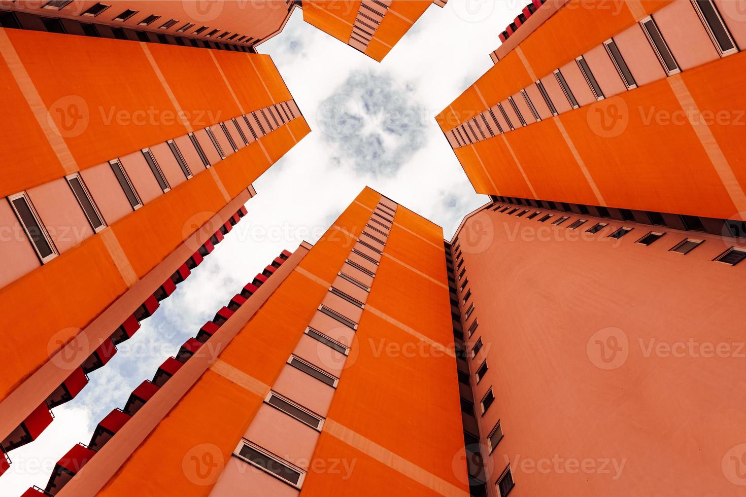 a high-rise with small red balkons with a view from below photo