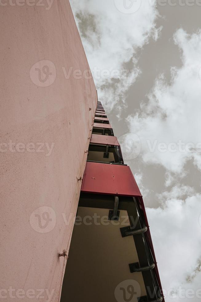 a high-rise with small red balkons with a view from below photo