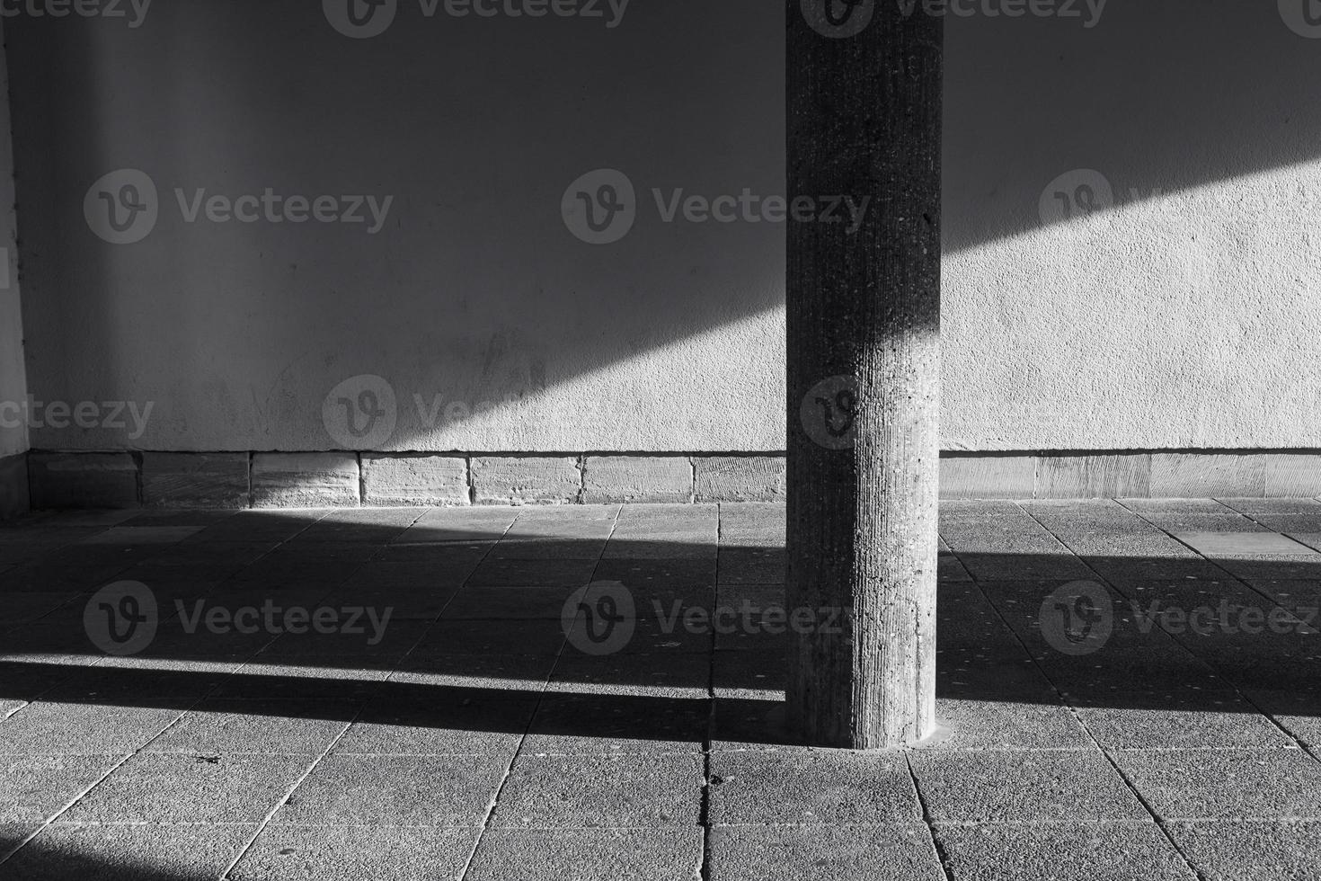 column of stone in front of a wall with shade and sunlight photo