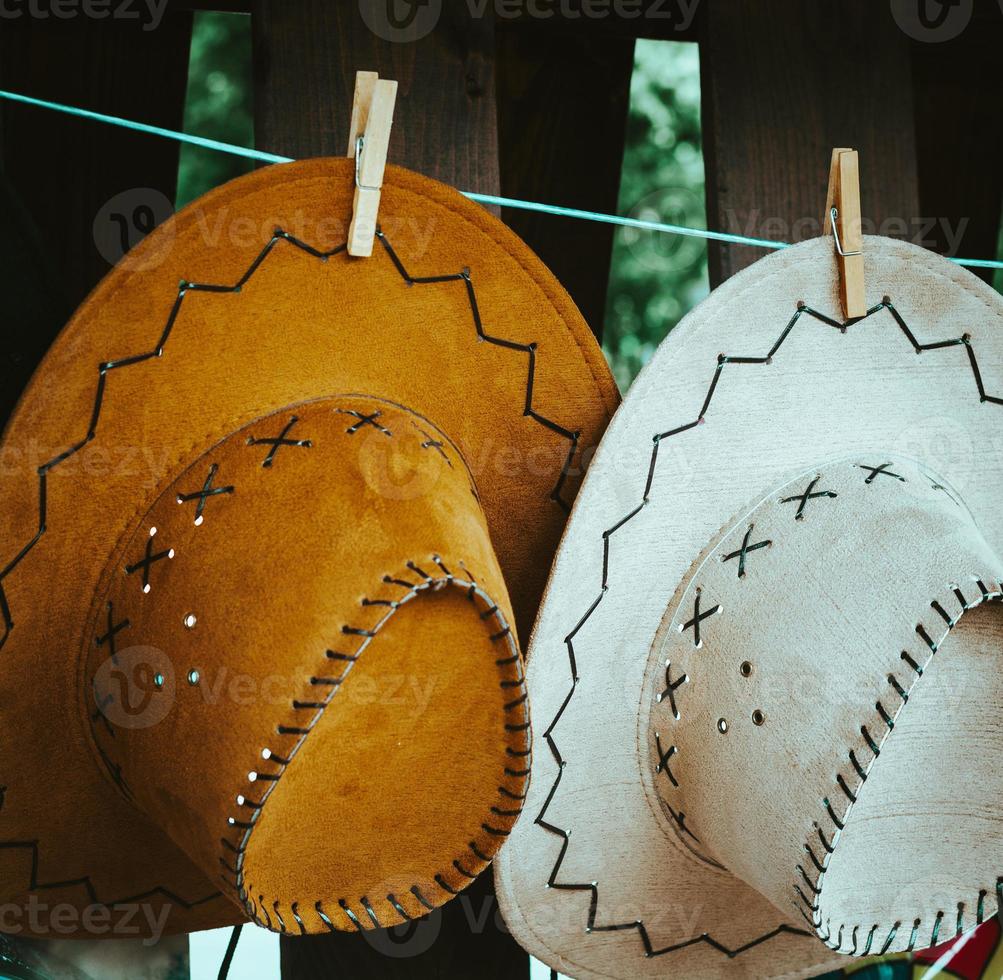 Two decorative leather hats hanging on a line photo