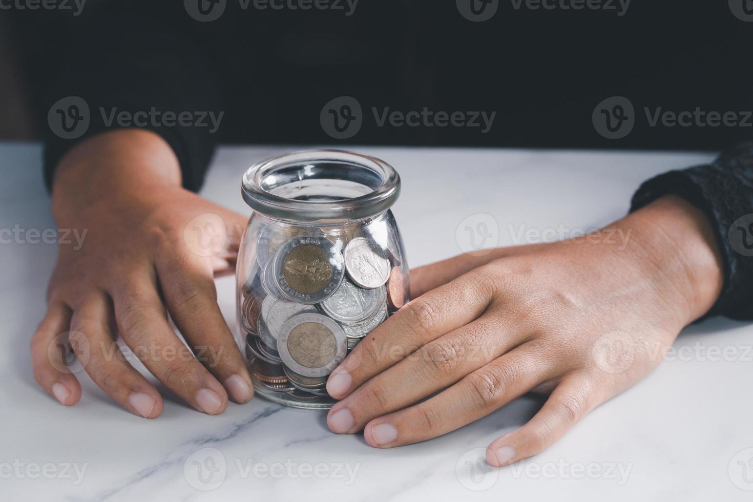 mano sosteniendo un frasco con monedero. concepto de ahorro de dinero. tono oscuro foto