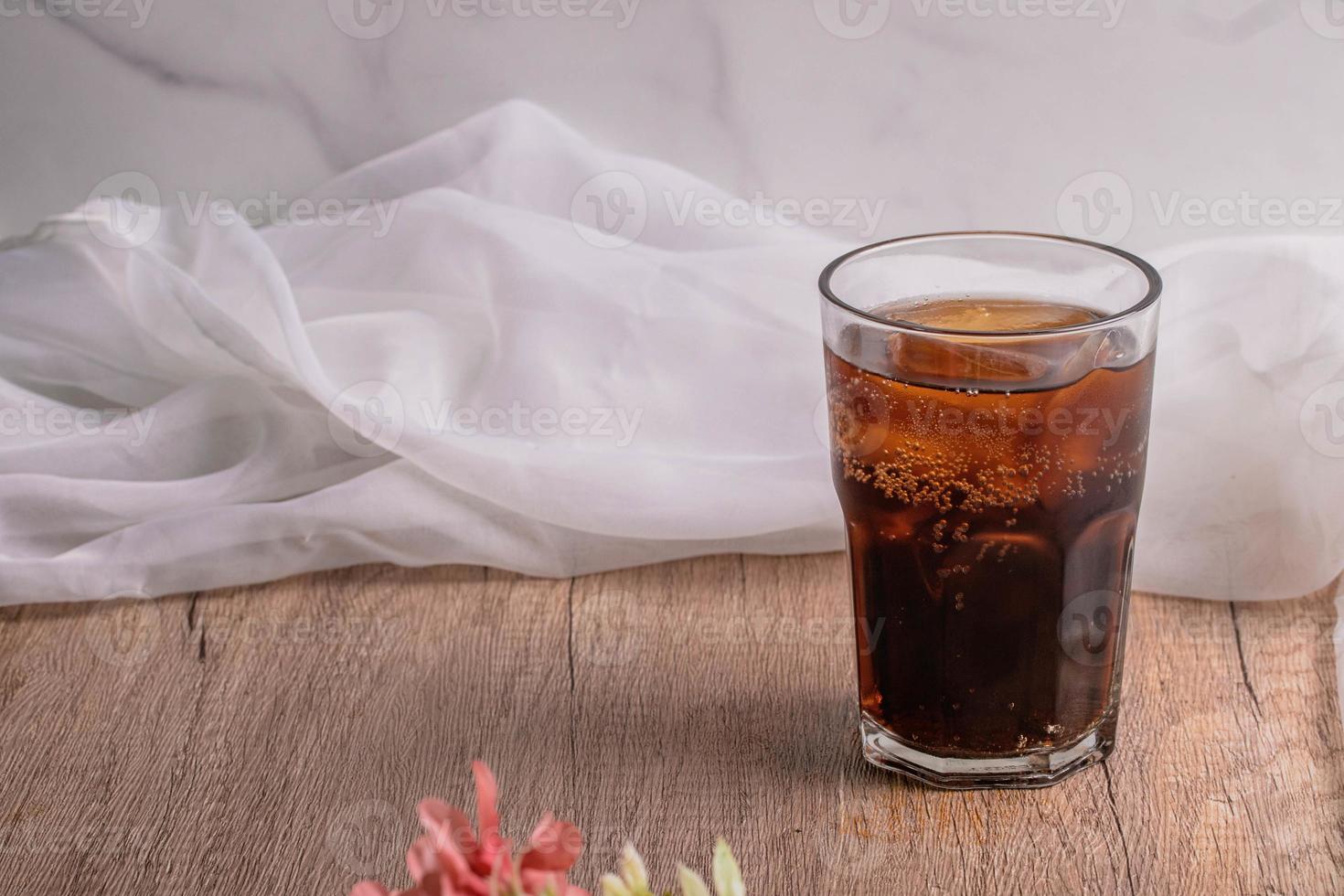 cola cola drink with ice in glass put on wooden background photo