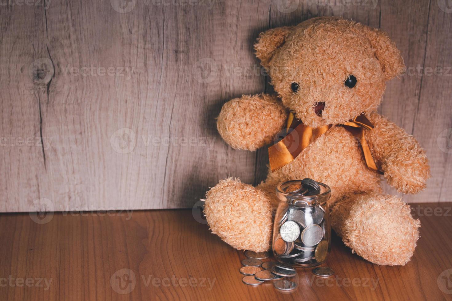 Glass bottle with coin purse and teddy bear. Casual money saving idea. photo