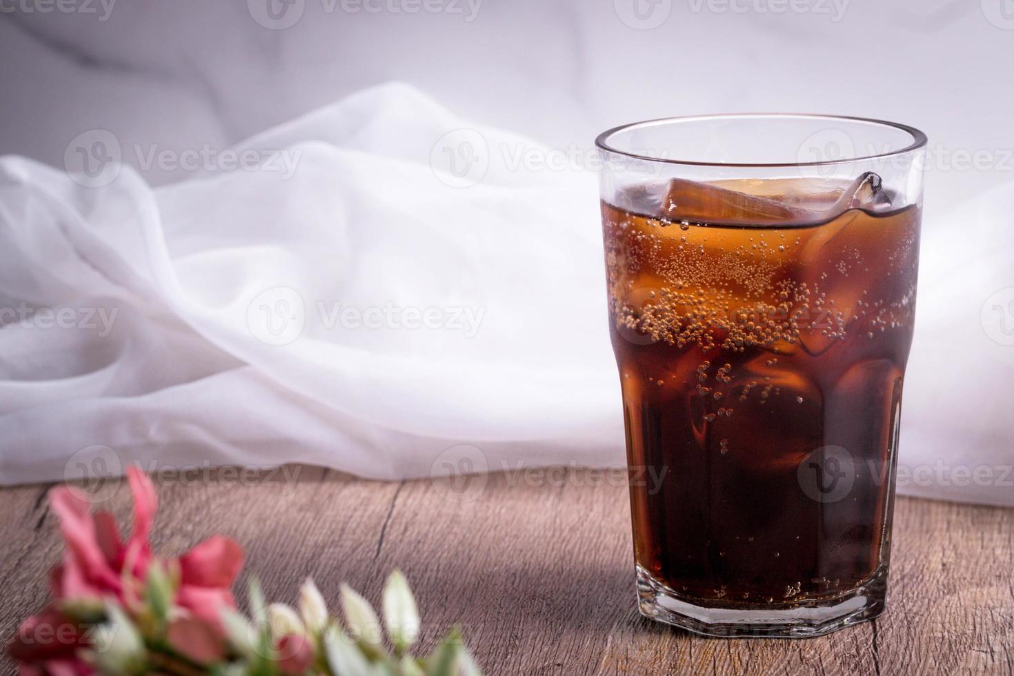 cola cola drink with ice in glass put on wooden background photo