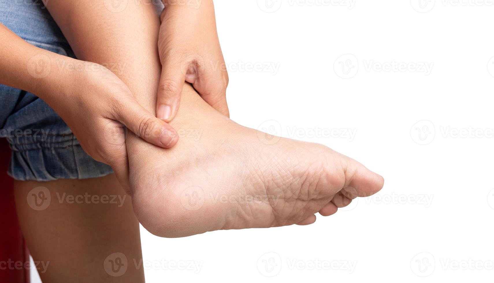 Woman sitting on chair with ankle pain using two hands holding leg photo