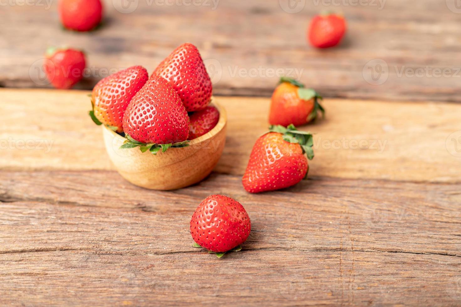 strawberries are in a wooden bowl placed on the old table. photo