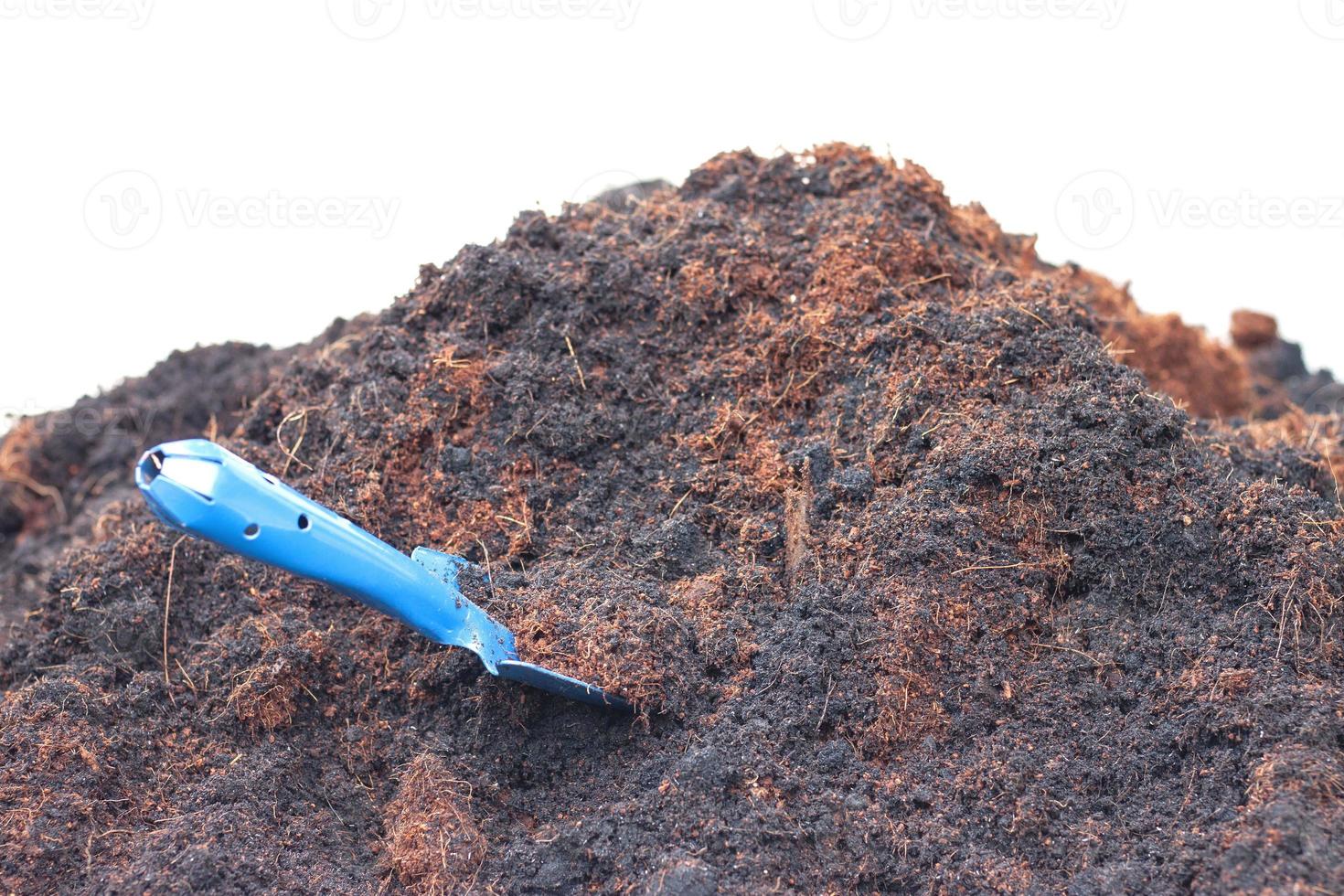 Pile of soil and coconut dust with a blue shovel isolated on white background. photo