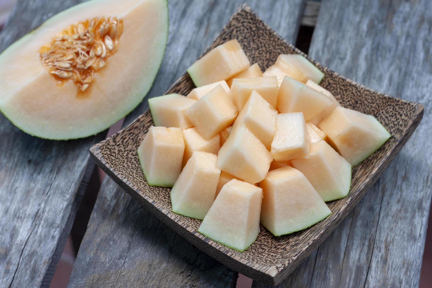 Sliced Cantaloupe in wooden plate on old table background. photo