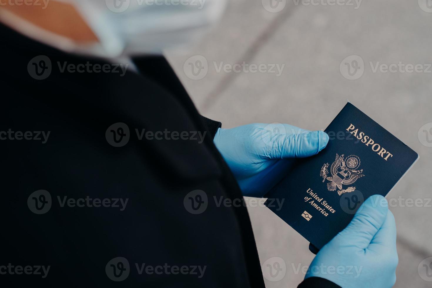 Unknown man tourist wears rubber medical gloves, holds passport, cannot travel during pandemic disease spread, prevents coronavirus. Negative impact on world tourism. Covid 19, danger, virus photo