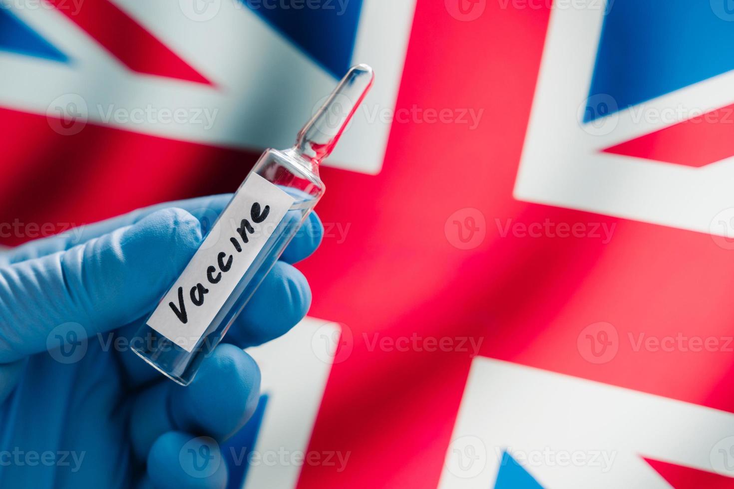 New coronavirus vaccine against UK flag as background. Fight against Covid-19. British medical research and vaccination. Medicine concept photo