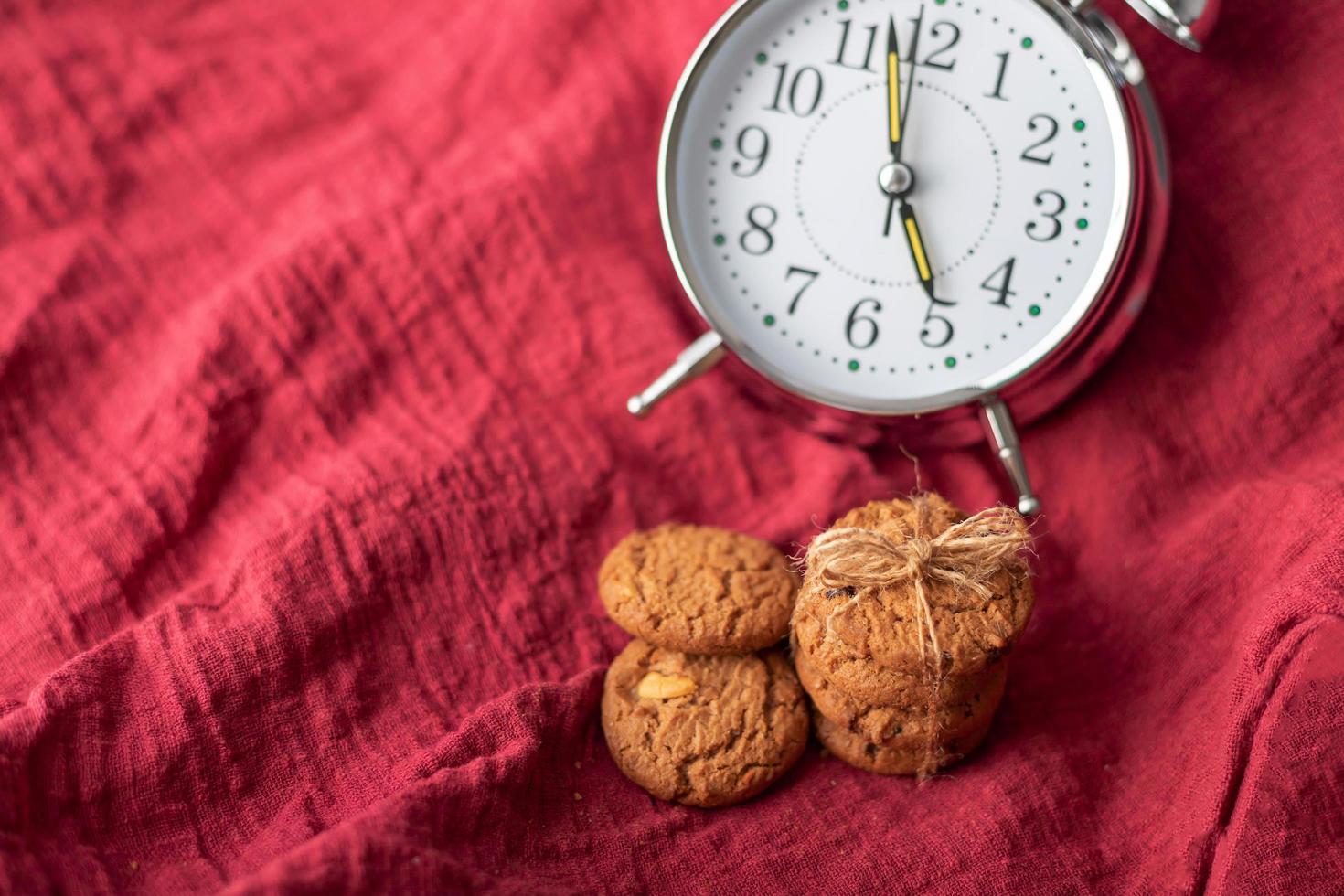 The clock and cookies place on the red fabric photo