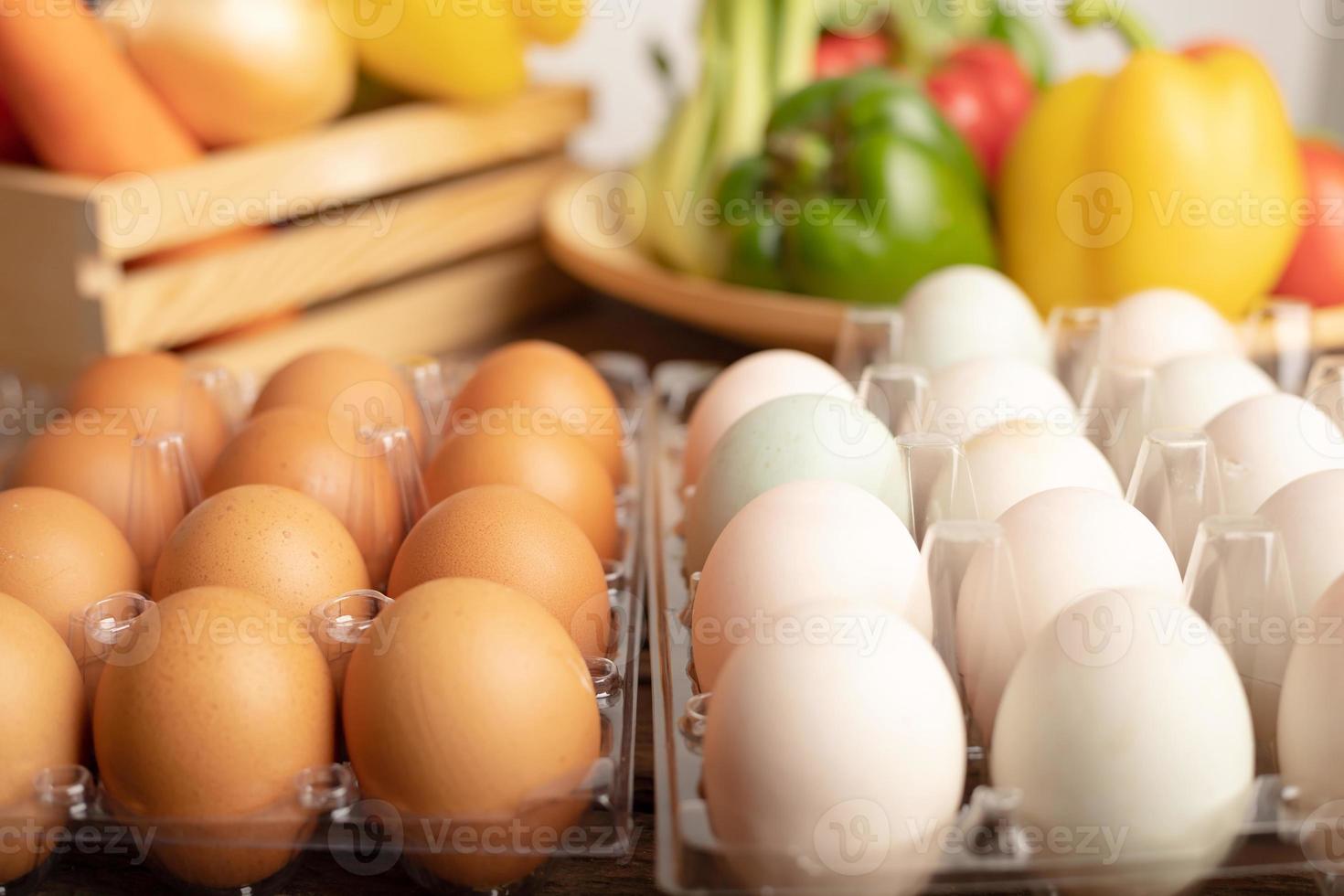 eggs of duck and chicken are placed on a wooden table with various vegetables photo